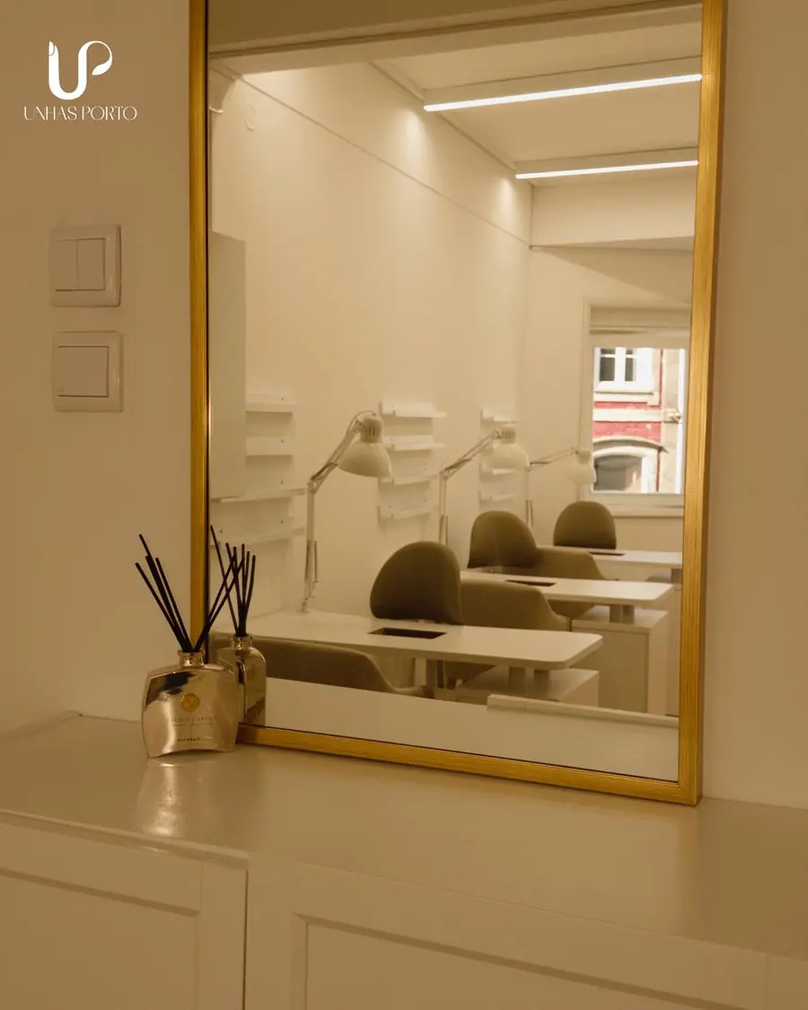 Espelho dourado com os postos de manicure refletidos ao fundo